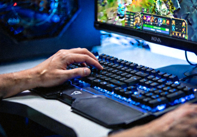 DOTA2选手Nova在比赛中专注操作键盘的特写，屏幕反射出游戏画面