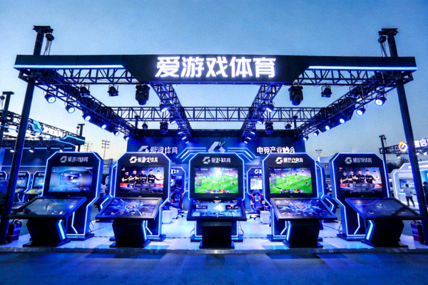爱游戏体育在电竞产业峰会的特装展台，蓝色灯光与互动屏幕